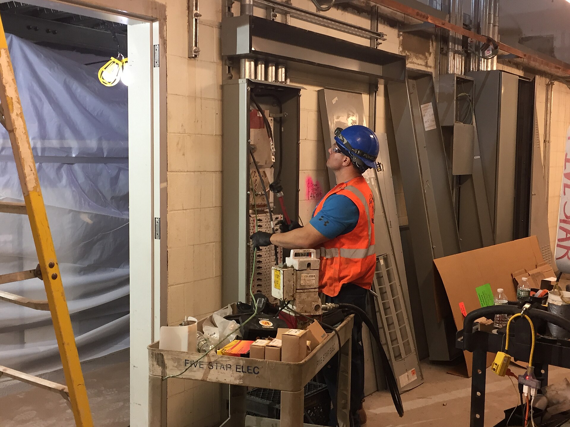 Licensed electrician in safety gear inspecting a commercial breaker panel