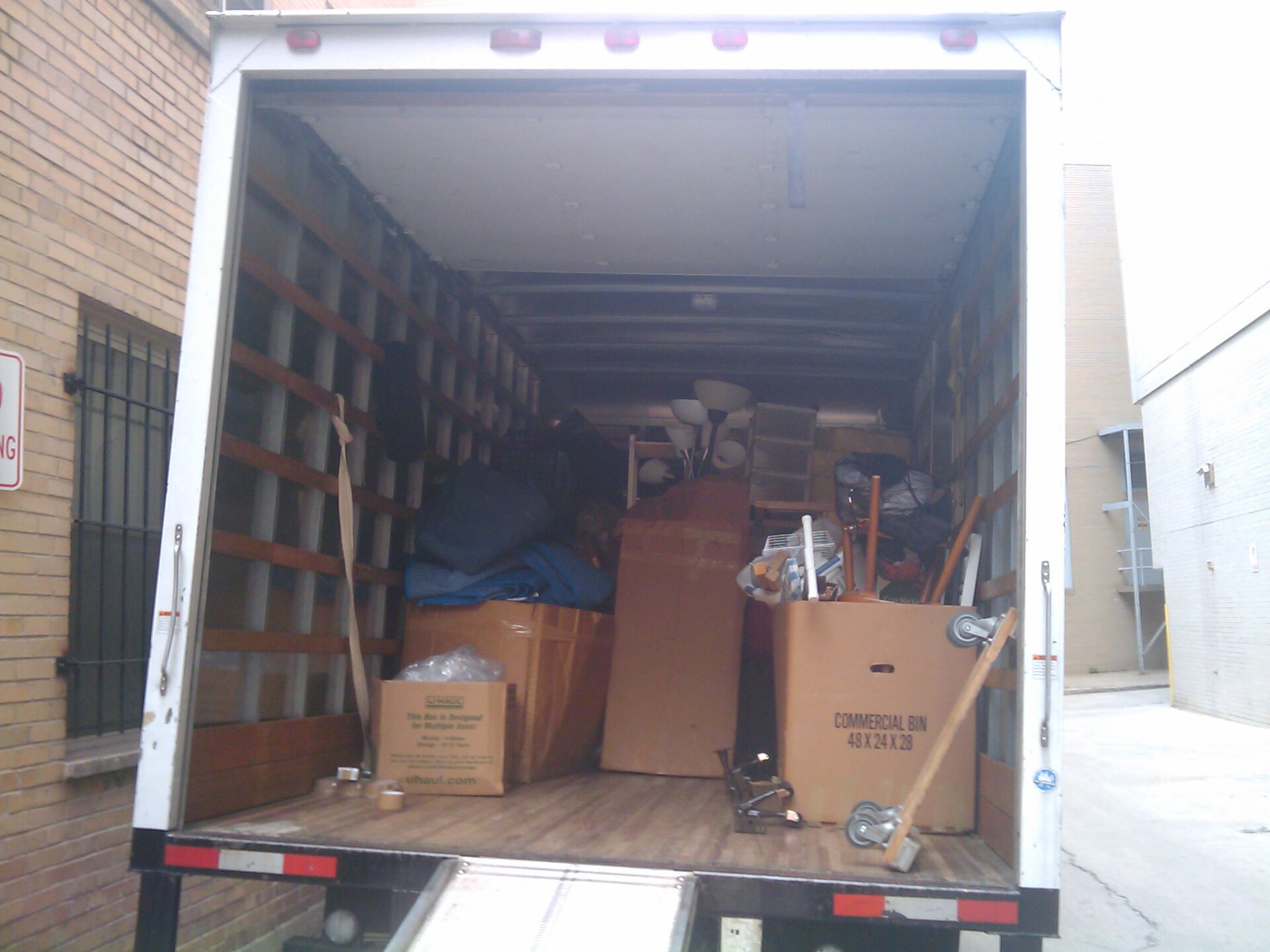 Moving truck cargo bay loaded with commercial moving boxes and hand dolly