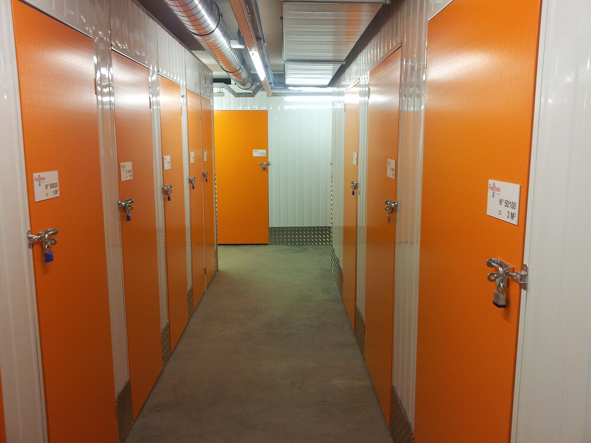 Indoor self-storage corridor with secure orange unit doors and padlocks